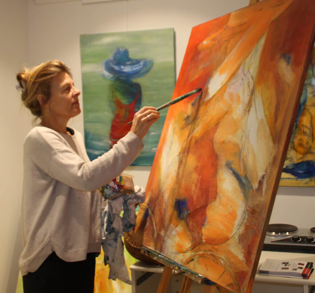 Gunhild Rasmussen maler i sit atelier og galleriet, i gang med let abstrakt og farverigt maleri